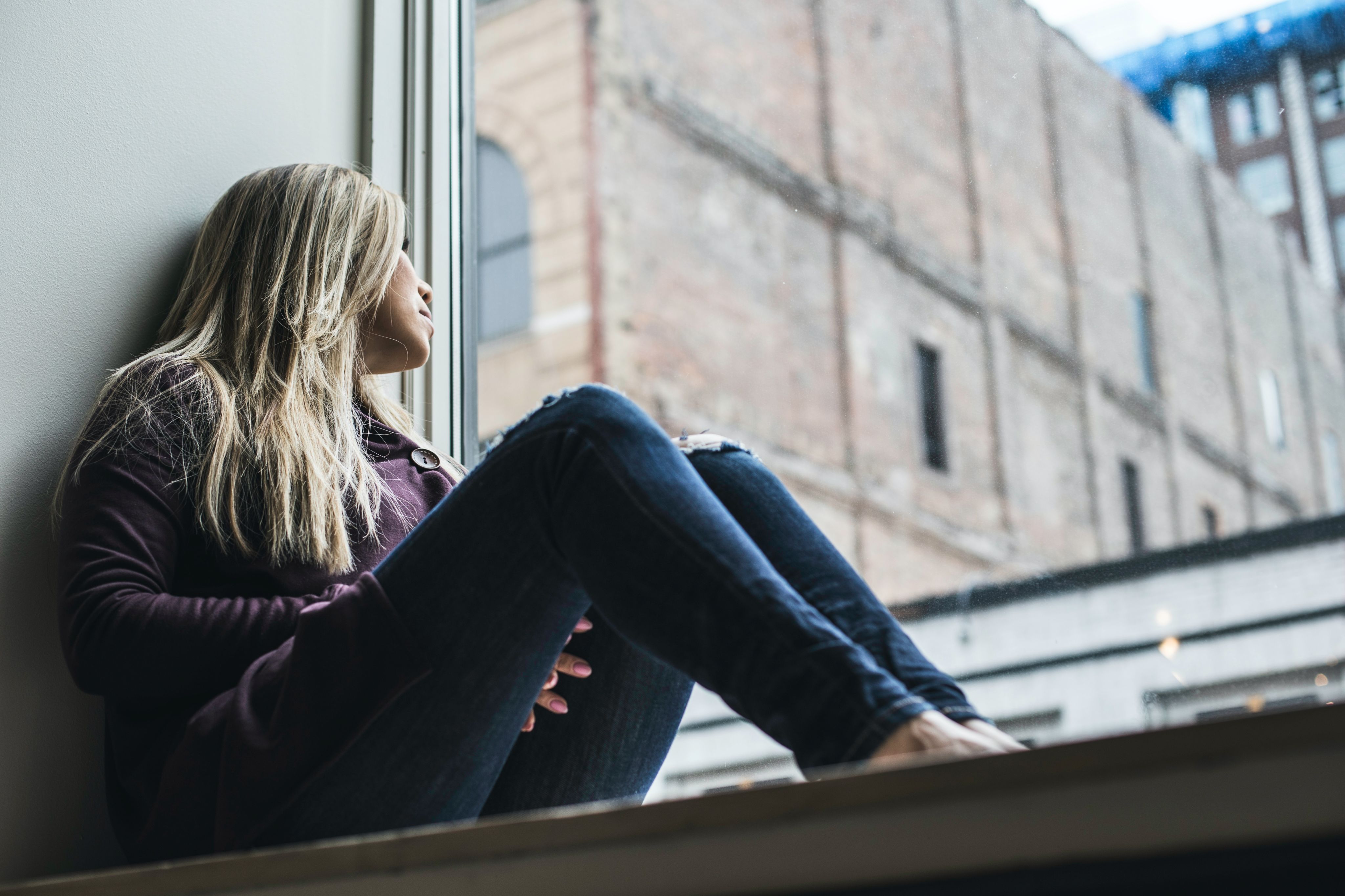 woman sitting on window watching sky