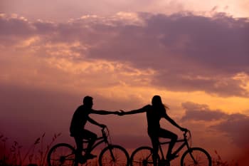 woman on bike reaching for man's hand 