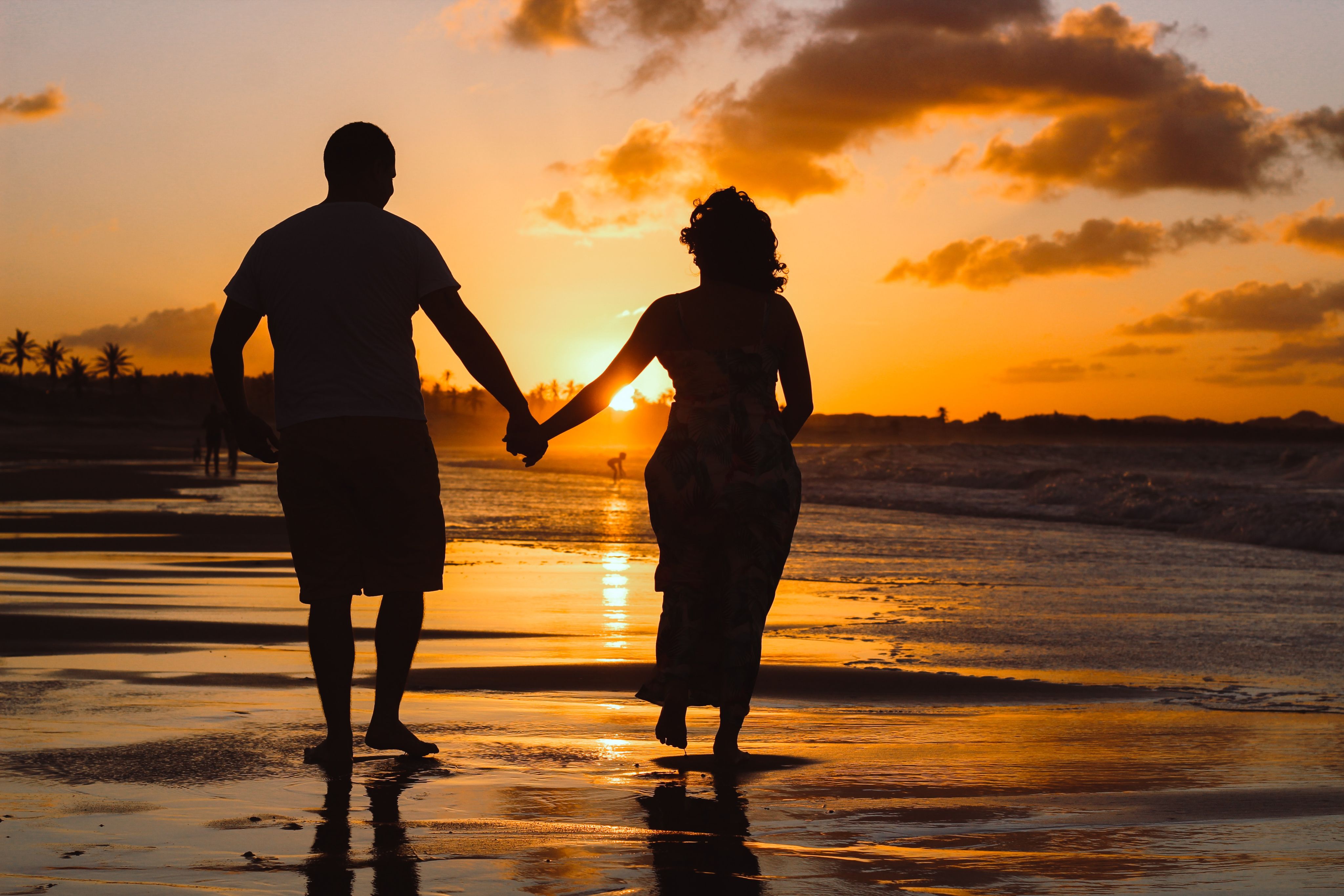 couple standing on body of water during golden hour