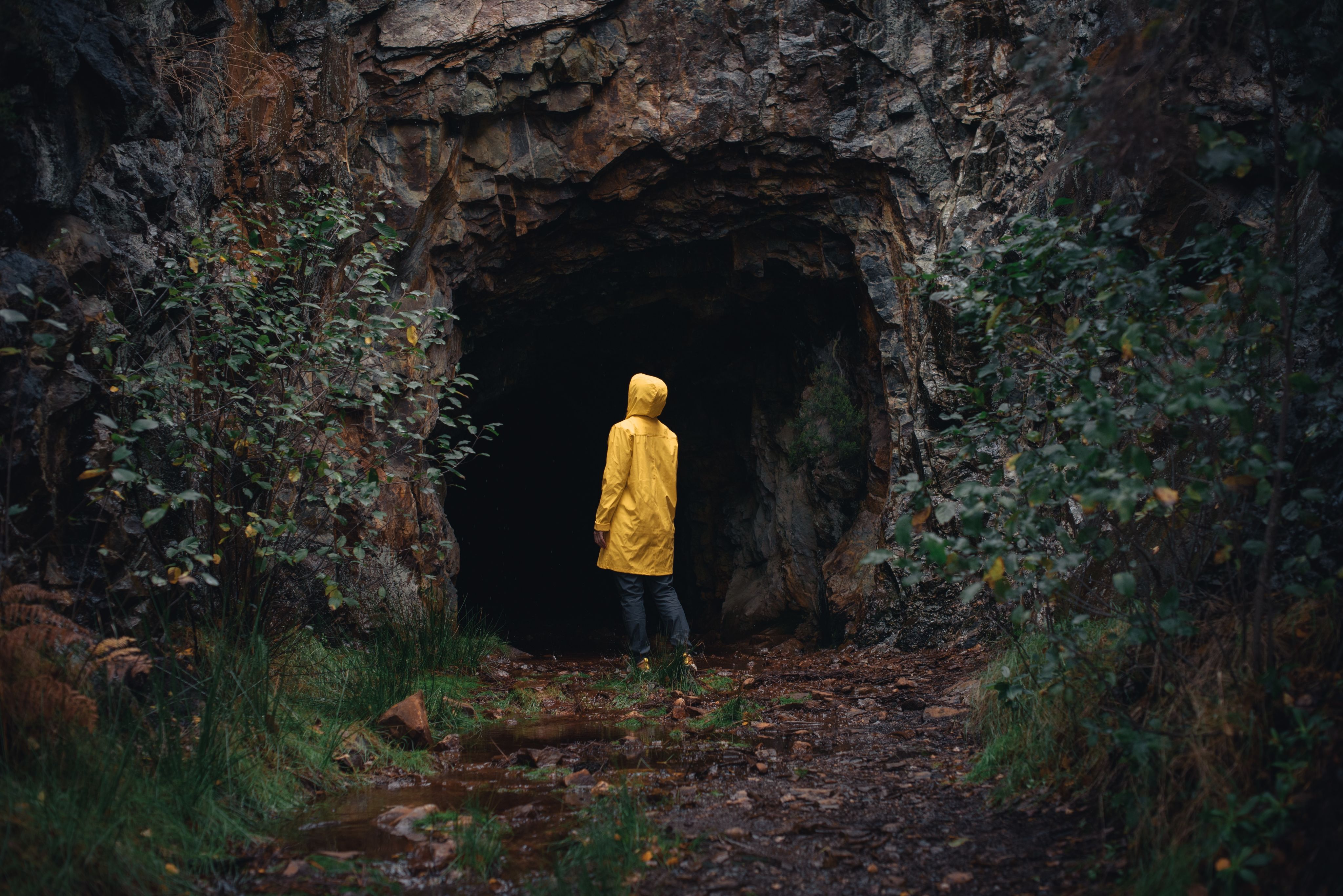 a person in a yellow jacket is standing in a cave