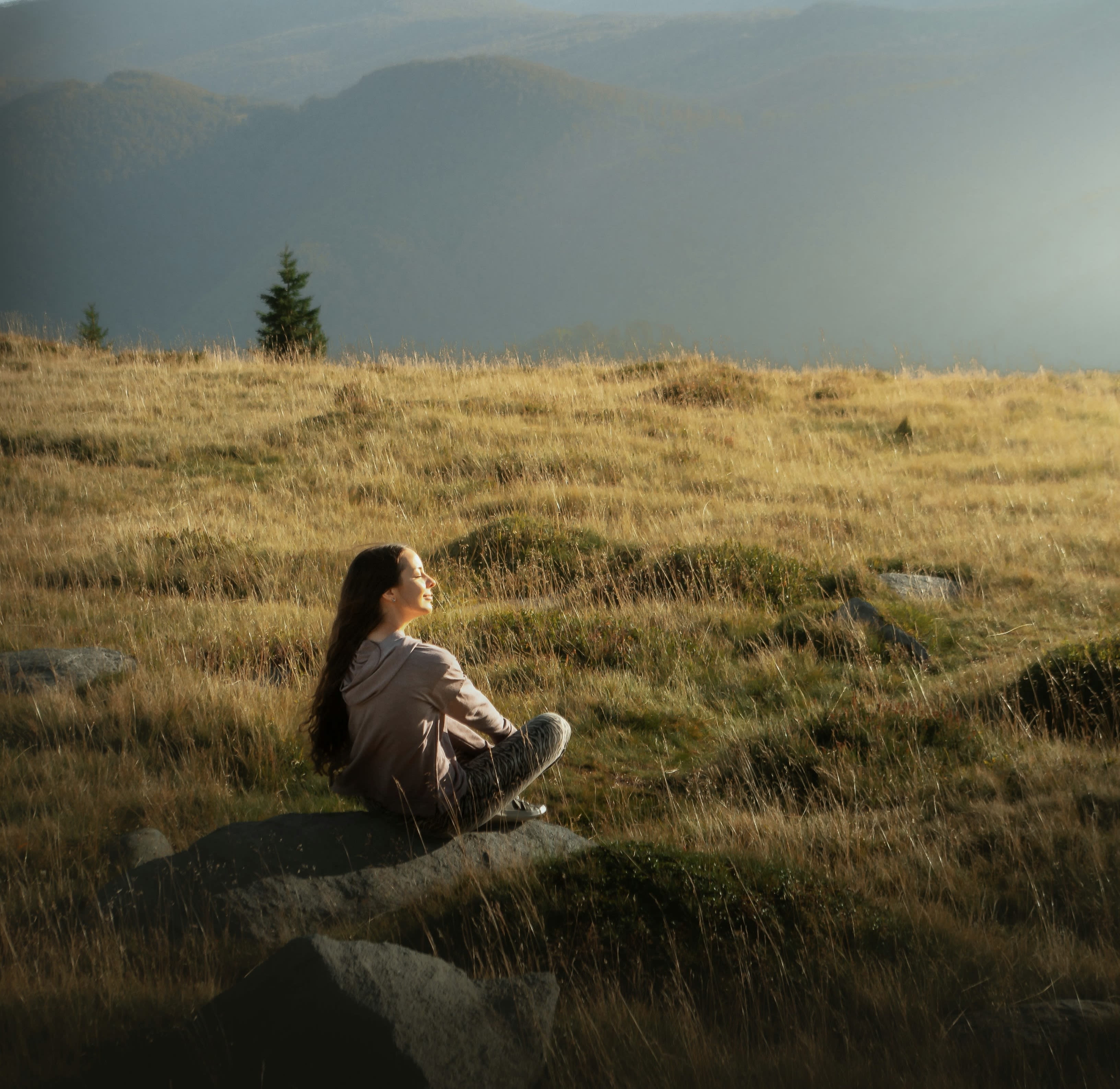woman in red jacket sitting on green grass field during daytime